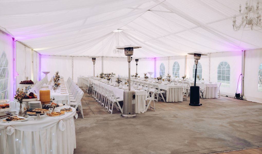 Location de salle de mariage : salle de réception décorée de fleurs et de lumières, tables dressées pour les invités