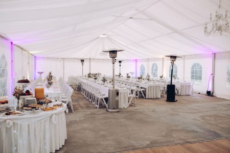 Location de salle de mariage : salle de réception décorée de fleurs et de lumières, tables dressées pour les invités