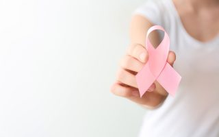 Femme tenant un ruban rose, symbole d'Octobre Rose et de la lutte contre le cancer du sein